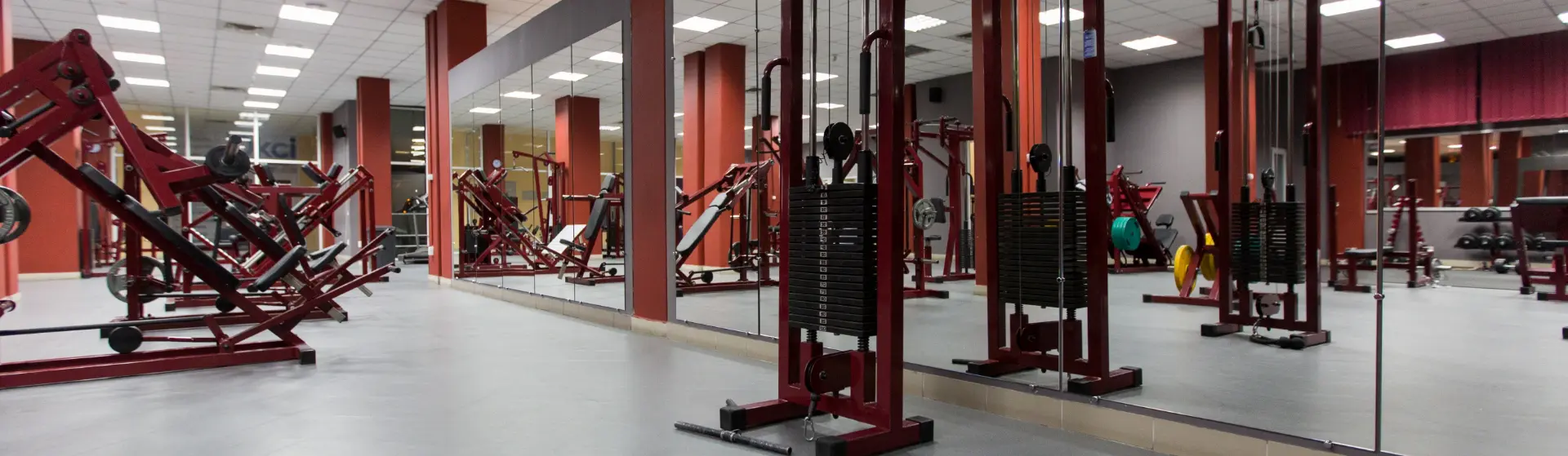 Fitnessstudio mit mehreren Krafttrainingsgeräten und großen Spiegeln