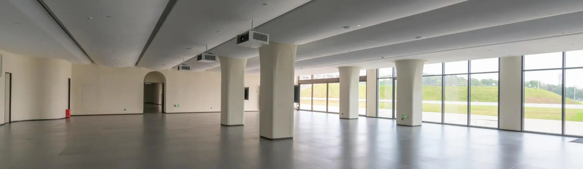 Leerer, moderner Innenraum mit großen Fensterfronten und Säulen