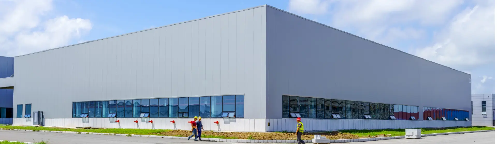Großes modernes Industriegebäude mit Bauarbeitern davor