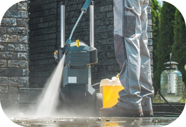 pressure-washer-cleaning Eine Person reinigt mit einem Hochdruckreiniger den Boden vor einem Haus